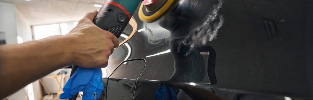 Cropped view of car detailing studio worker removing scratches and polishing car with electrical polisher