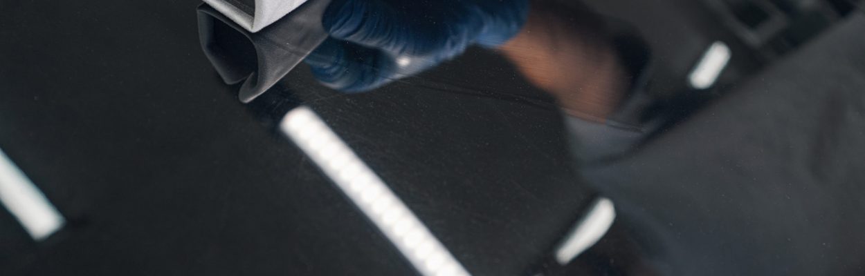 Close up of man applying ceramic coating on black car at detailing service